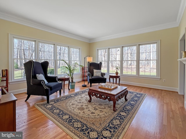 sitting room with baseboards, light wood finished floors, a fireplace, and crown molding