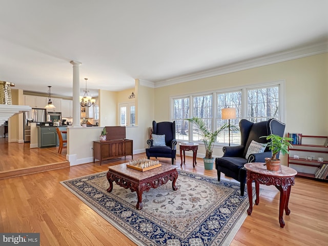 living room with light wood finished floors, decorative columns, a chandelier, and crown molding