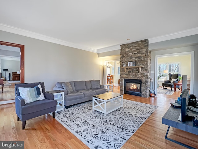 living room featuring an inviting chandelier, a fireplace, ornamental molding, and wood finished floors