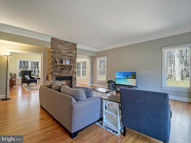 living area featuring ornamental molding, baseboards, a stone fireplace, and light wood finished floors