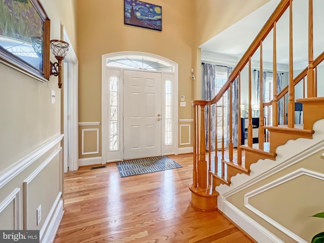 entryway with light wood-style floors, a wealth of natural light, a wainscoted wall, and a decorative wall