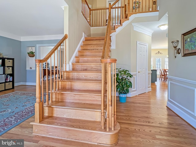 stairs featuring wainscoting, wood finished floors, and crown molding