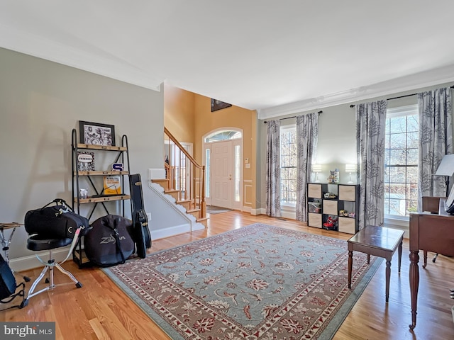 entryway with a healthy amount of sunlight, baseboards, stairway, and wood finished floors