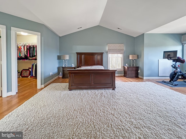 bedroom featuring visible vents, vaulted ceiling, a spacious closet, a closet, and light wood-type flooring