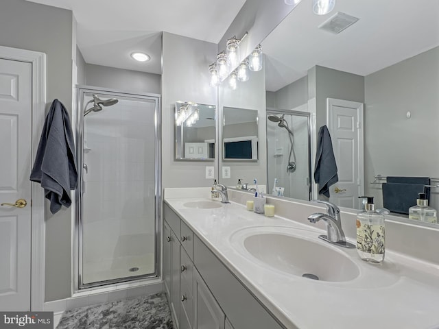 bathroom featuring double vanity, a stall shower, visible vents, and a sink