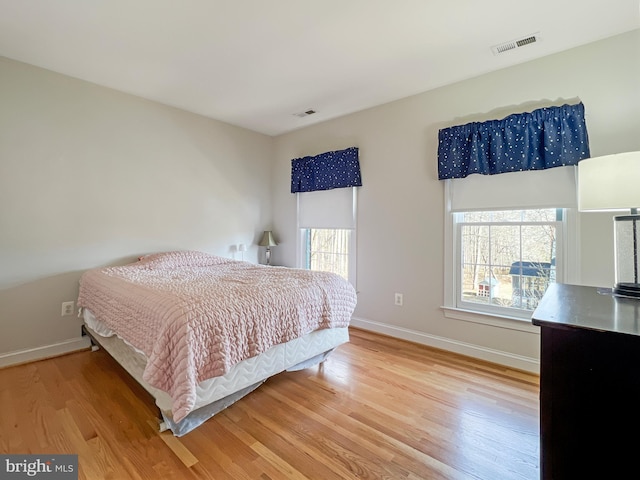 bedroom featuring visible vents, baseboards, and wood finished floors