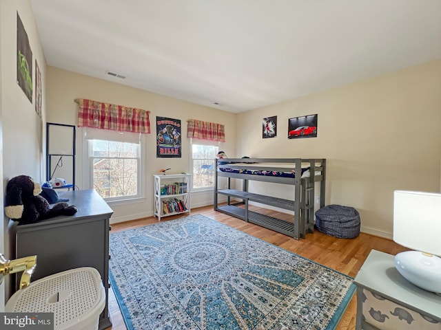 bedroom featuring visible vents, baseboards, and wood finished floors