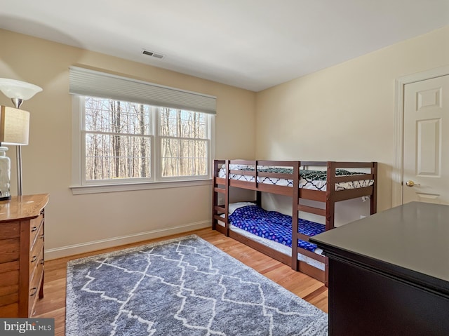 bedroom featuring visible vents, baseboards, and wood finished floors