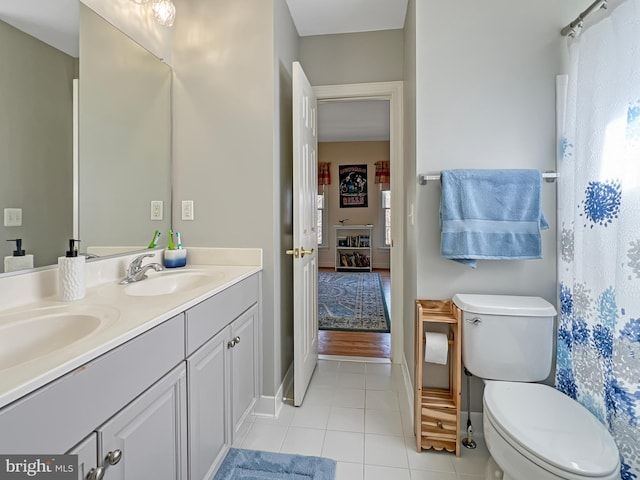 ensuite bathroom with double vanity, a sink, toilet, and tile patterned floors