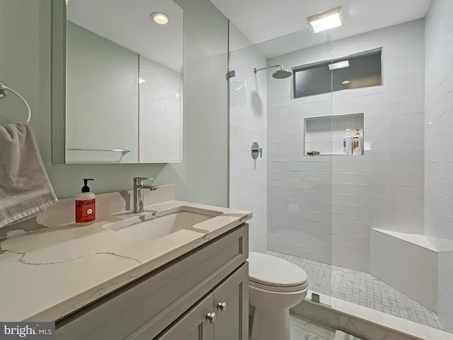 bathroom featuring a walk in shower, toilet, and vanity