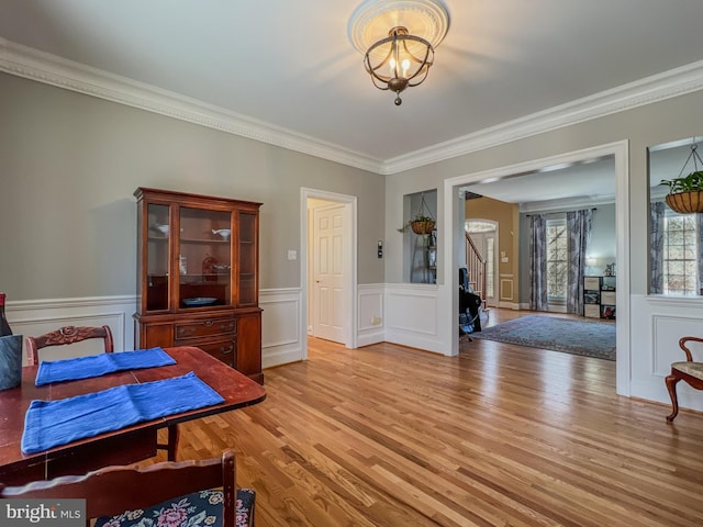 bedroom featuring light wood-style floors, crown molding, and wainscoting