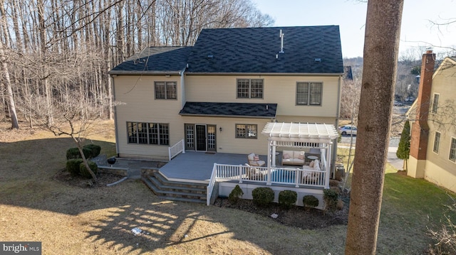 back of property with a yard, a shingled roof, a wooden deck, and a pergola