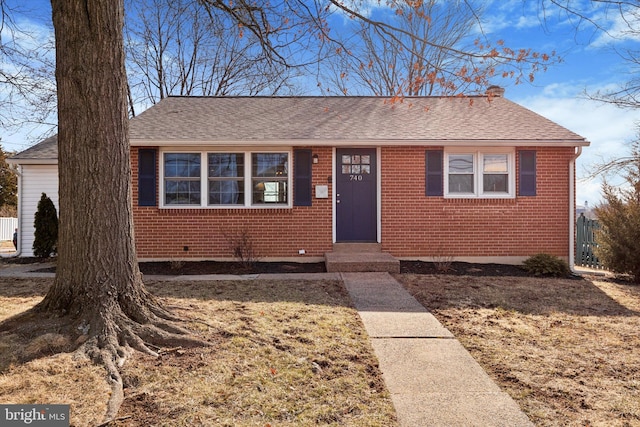 view of front of property featuring a shingled roof, fence, and brick siding