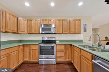 kitchen featuring dark wood finished floors, stainless steel appliances, a sink, and recessed lighting