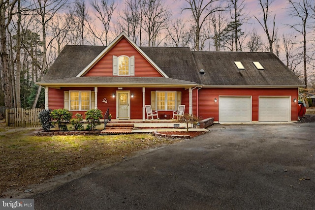 view of front of house featuring a porch, a garage, fence, driveway, and roof with shingles