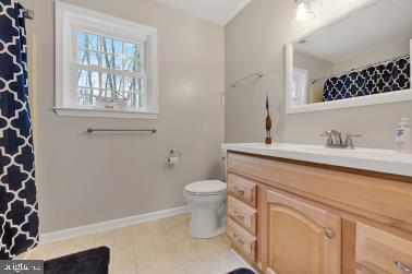 full bathroom featuring curtained shower, baseboards, vanity, and toilet