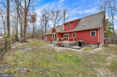 back of property with a lawn and fence