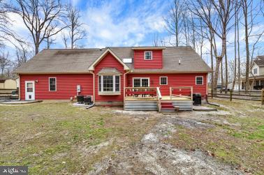 rear view of property featuring fence, a deck, and a lawn