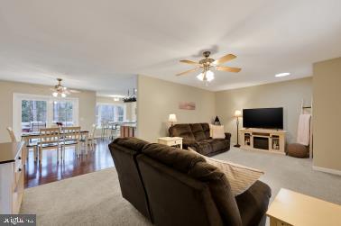 carpeted living area featuring baseboards and a ceiling fan