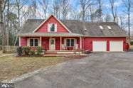 view of front of house featuring an attached garage, aphalt driveway, and a porch