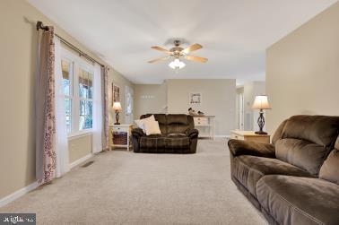 living room with carpet, a ceiling fan, and baseboards