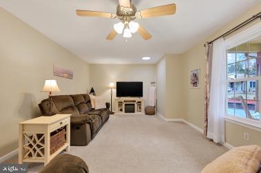 living room with carpet flooring, a ceiling fan, and baseboards