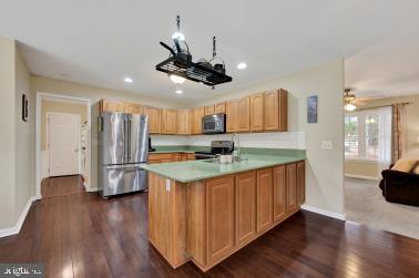 kitchen featuring recessed lighting, a peninsula, light countertops, appliances with stainless steel finishes, and dark wood finished floors