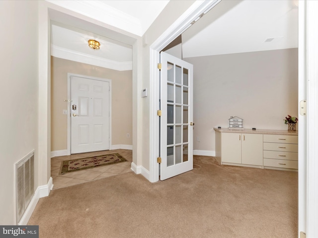 foyer featuring crown molding, light tile patterned floors, light colored carpet, visible vents, and baseboards