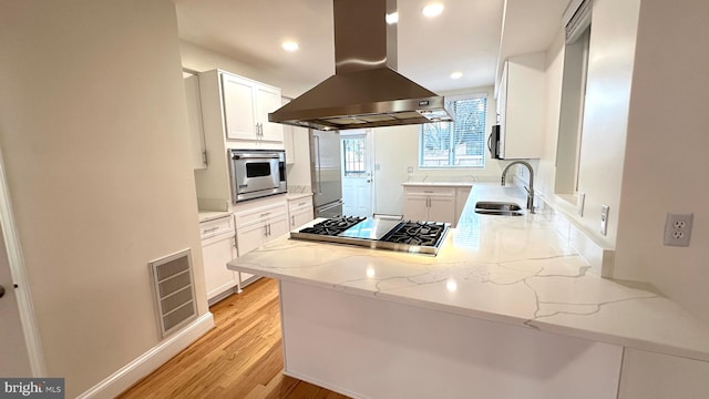 kitchen with white cabinets, sink, and island exhaust hood