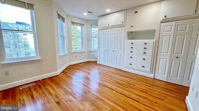 unfurnished bedroom with two closets and light wood-type flooring