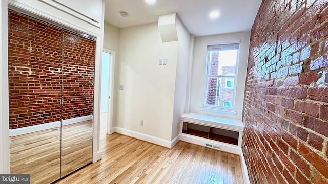 interior space featuring light wood-type flooring and brick wall