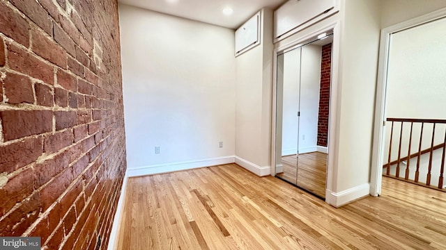 interior space featuring brick wall and light hardwood / wood-style flooring