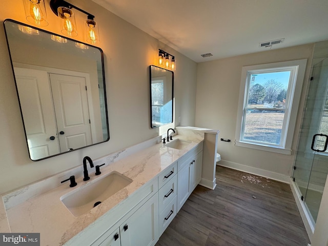 bathroom with a shower stall, visible vents, wood finished floors, and a sink
