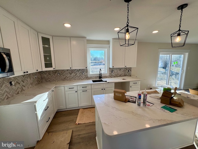 kitchen featuring dark wood finished floors, white cabinets, stainless steel microwave, and a sink