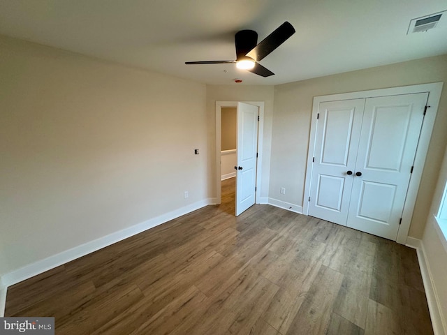 unfurnished bedroom featuring a closet, visible vents, baseboards, wood finished floors, and a ceiling fan