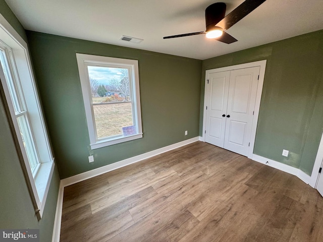 unfurnished bedroom with baseboards, visible vents, a closet, and wood finished floors