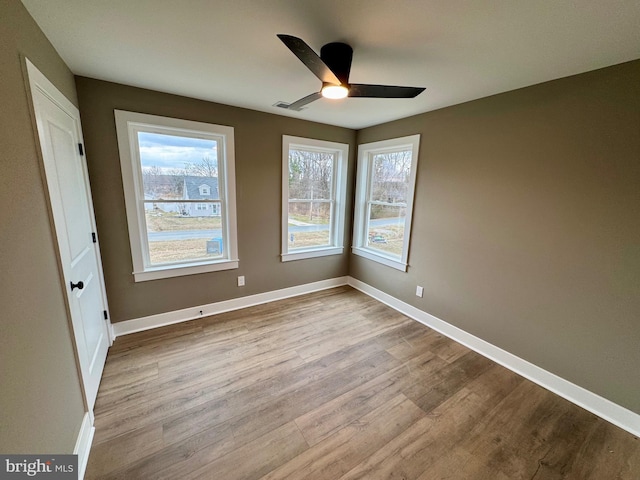 unfurnished bedroom with baseboards, multiple windows, and wood finished floors
