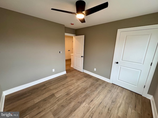 unfurnished bedroom with baseboards, wood finished floors, and a ceiling fan