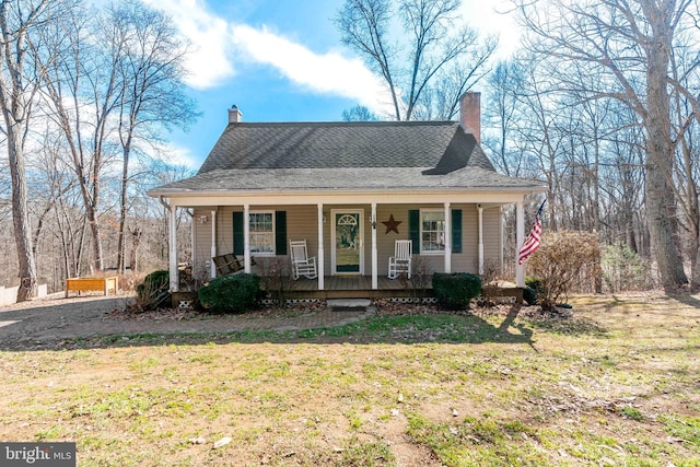 view of front of home with covered porch, roof with shingles, a chimney, and a front lawn