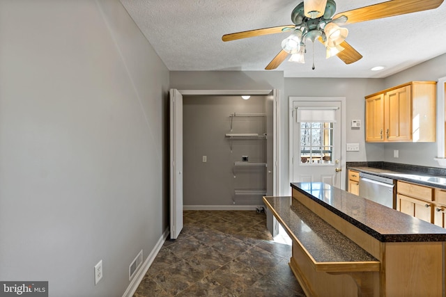 kitchen featuring a textured ceiling, visible vents, baseboards, stainless steel dishwasher, and dark countertops