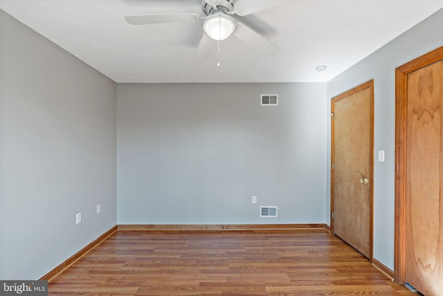 unfurnished room with wood finished floors, visible vents, and baseboards