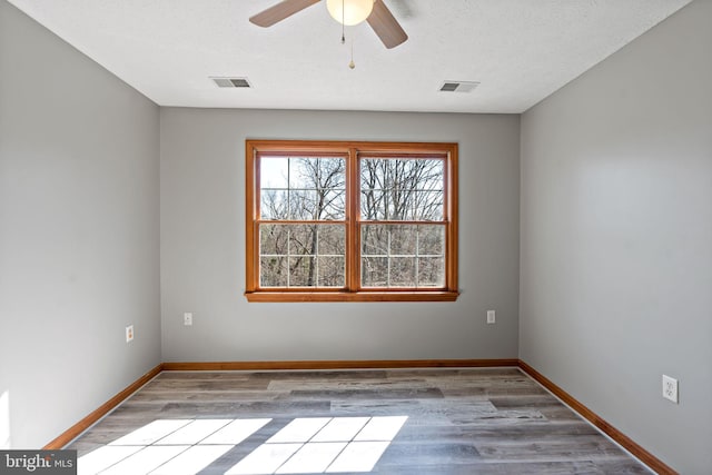 unfurnished room with baseboards, visible vents, and wood finished floors