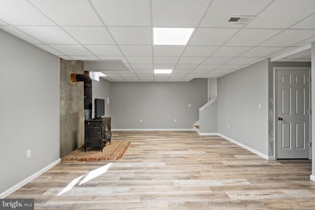 finished basement featuring a paneled ceiling, light wood-style flooring, visible vents, baseboards, and stairway