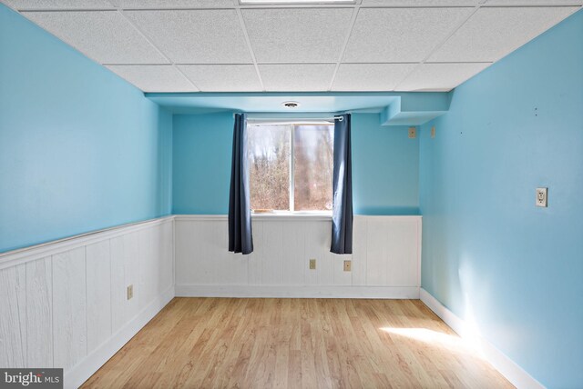 spare room featuring wainscoting, a drop ceiling, and wood finished floors