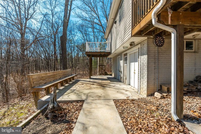 view of side of property featuring stairs, brick siding, and a wooden deck