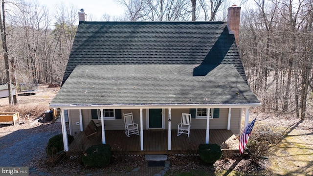 view of front of home featuring a shingled roof, a chimney, and a porch