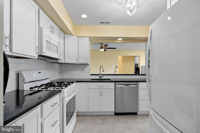 kitchen featuring sink, backsplash, white appliances, and white cabinetry