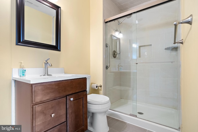 bathroom featuring tile patterned floors, vanity, a shower with shower door, and toilet