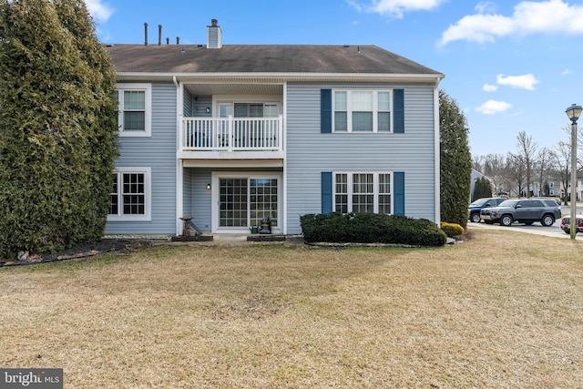 back of house featuring a balcony and a lawn