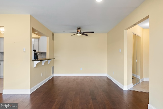 unfurnished living room with ceiling fan, dark hardwood / wood-style floors, and sink